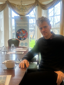 Arnaud Vallet with a compassionate mental health banner behind him