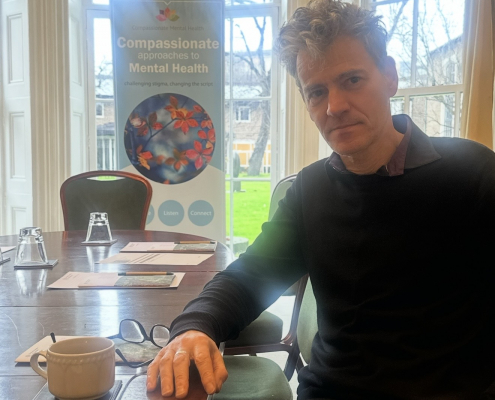Arnaud Vallet with a compassionate mental health banner behind him