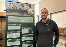 photo of Rob Sage by a banner with history of Lester sisters who founded Kingsley Hall