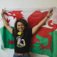 Amuta Garud with her arms in the air and a Welsh flag behind her