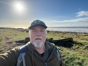 Andy Chyba looking at the camera with a blue sky and seascape behind him