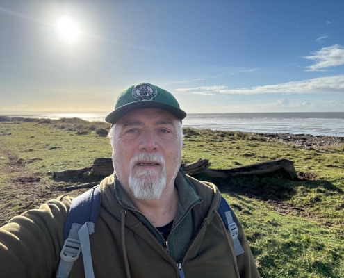Andy Chyba looking at the camera with a blue sky and seascape behind him