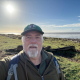 Andy Chyba looking at the camera with a blue sky and seascape behind him